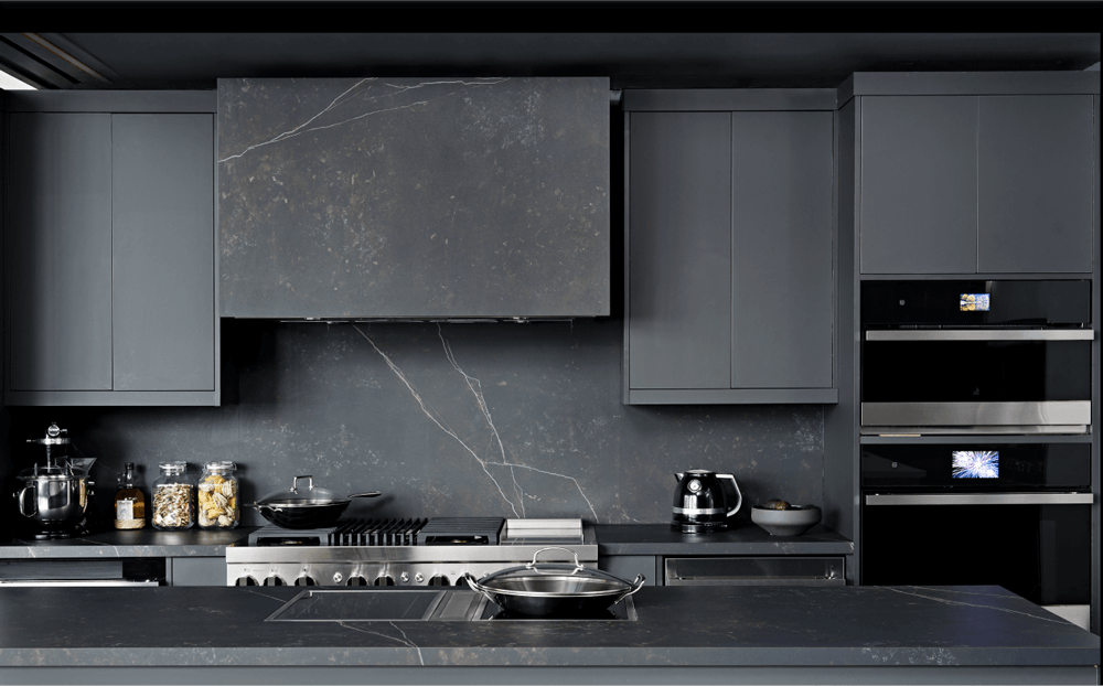 A JennAir Induction Cooktop installed in a dark, modern kitchen with other JennAir Brand appliances.  A JennAir Induction Cooktop installed in a dark, modern kitchen with other JennAir Brand appliances.